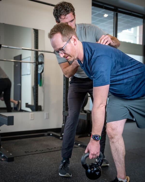 Physiotherapist guiding a man during kettlebell exercise at South Island Physiotherapy.