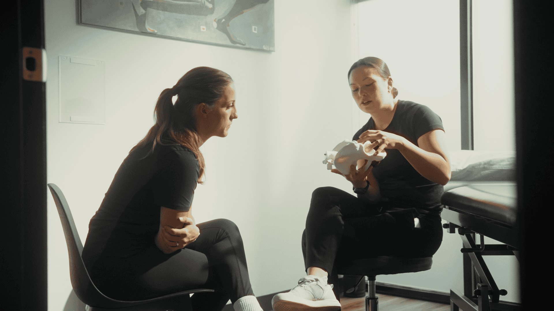 Physiotherapist explaining treatment to patient in clinic setting.