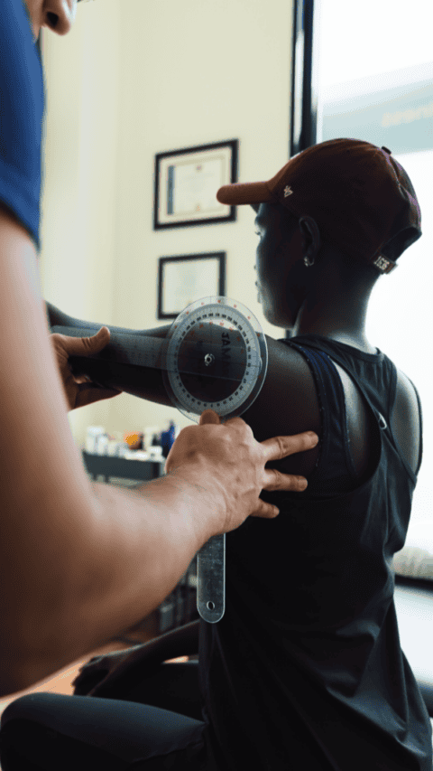 Physiotherapist measuring shoulder range of motion for injury assessment.