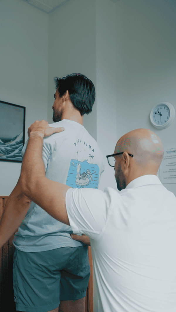 Physiotherapist assessing patient's shoulder during physiotherapy session.