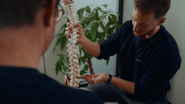 Physiotherapist explaining spinal anatomy to patient in clinic.