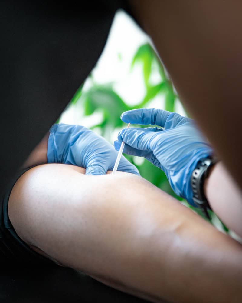 Close-up of a physiotherapist administering injection to a patient's arm, focusing on rehabilitation.