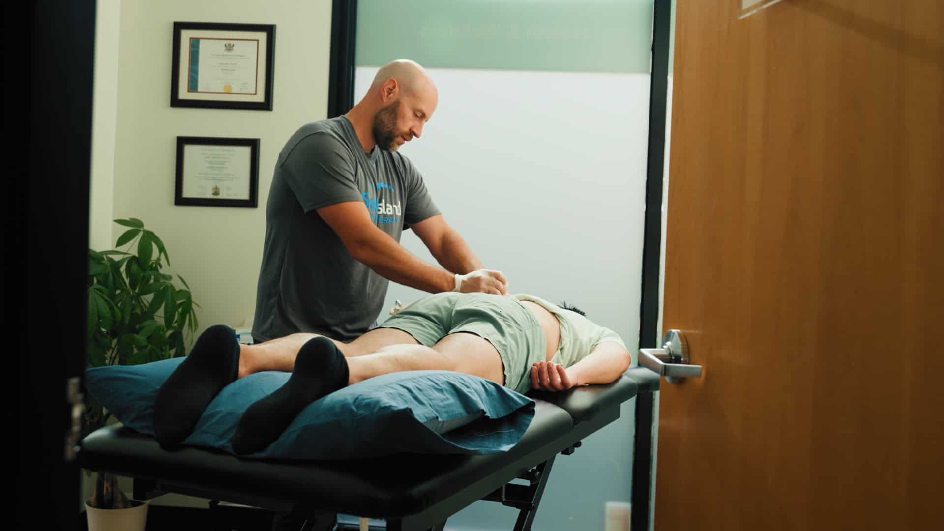 Physiotherapy session with a therapist working on a patient's leg and hip mobility.