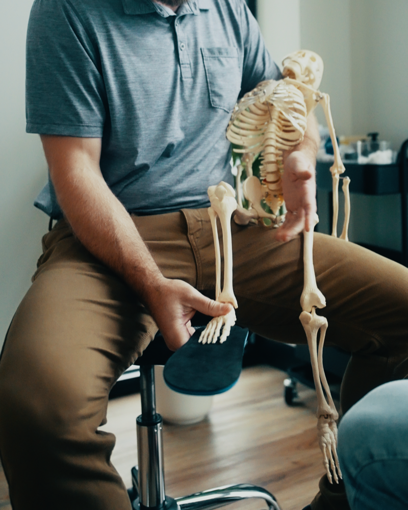 Male physiotherapist demonstrating spine anatomy during consultation.