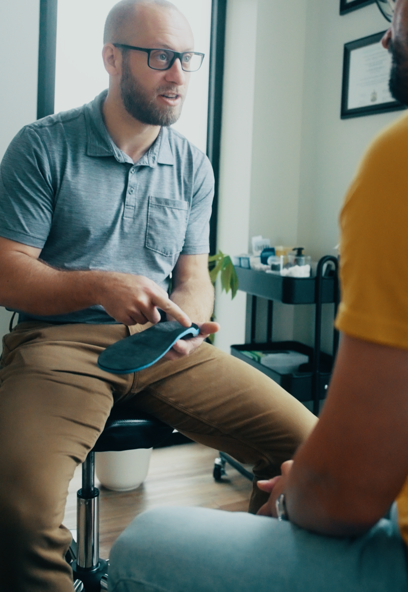 Male physiotherapist consulting with patient in clinic setting, discussing treatment options.