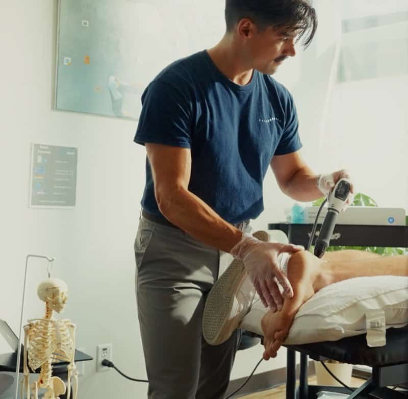 Physiotherapist performing manual therapy on patient in a clinical setting.