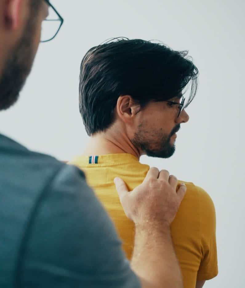 Physiotherapist providing shoulder assessment to a patient in a clinic setting.
