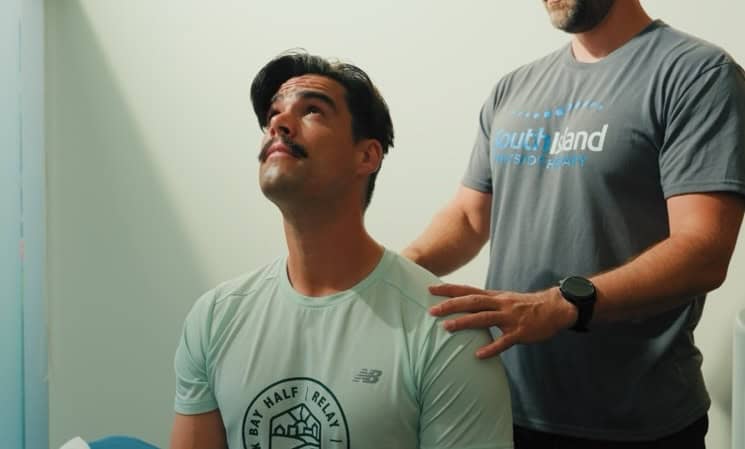 Male patient receiving physiotherapy treatment from a therapist at South Island Physio clinic.