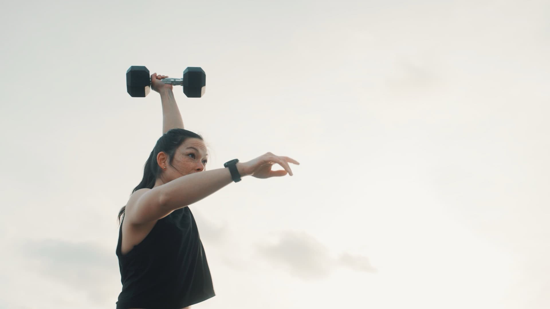 Woman lifting a dumbbell during strength training session.